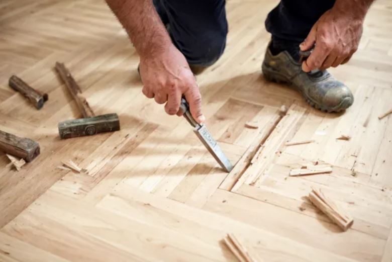 Artisan utilisant une ponceuse monobrosse pour l'égrenage et la finition d'un parquet à Rennes